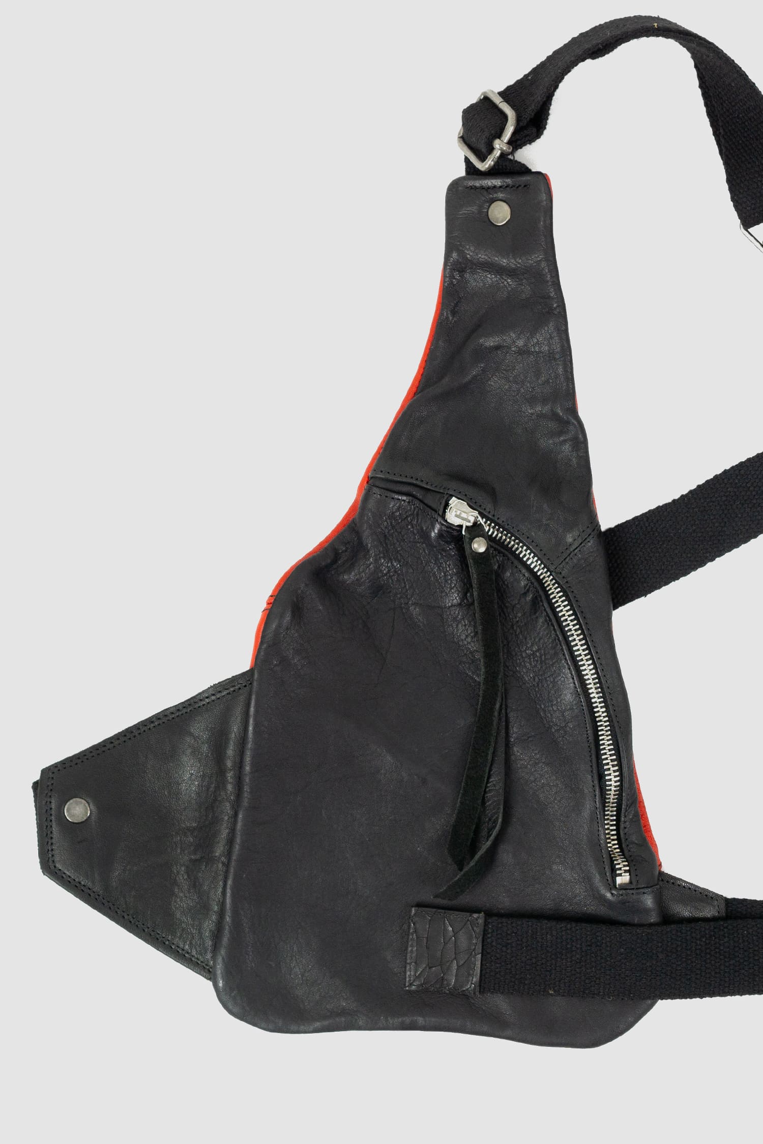 0.Hide - left detail view of vegetable tanned black and red horsehide leather cargo vest from the permanent collection with two types of horse leather shoulder panels, adjustable cotton straps and zippered pockets.