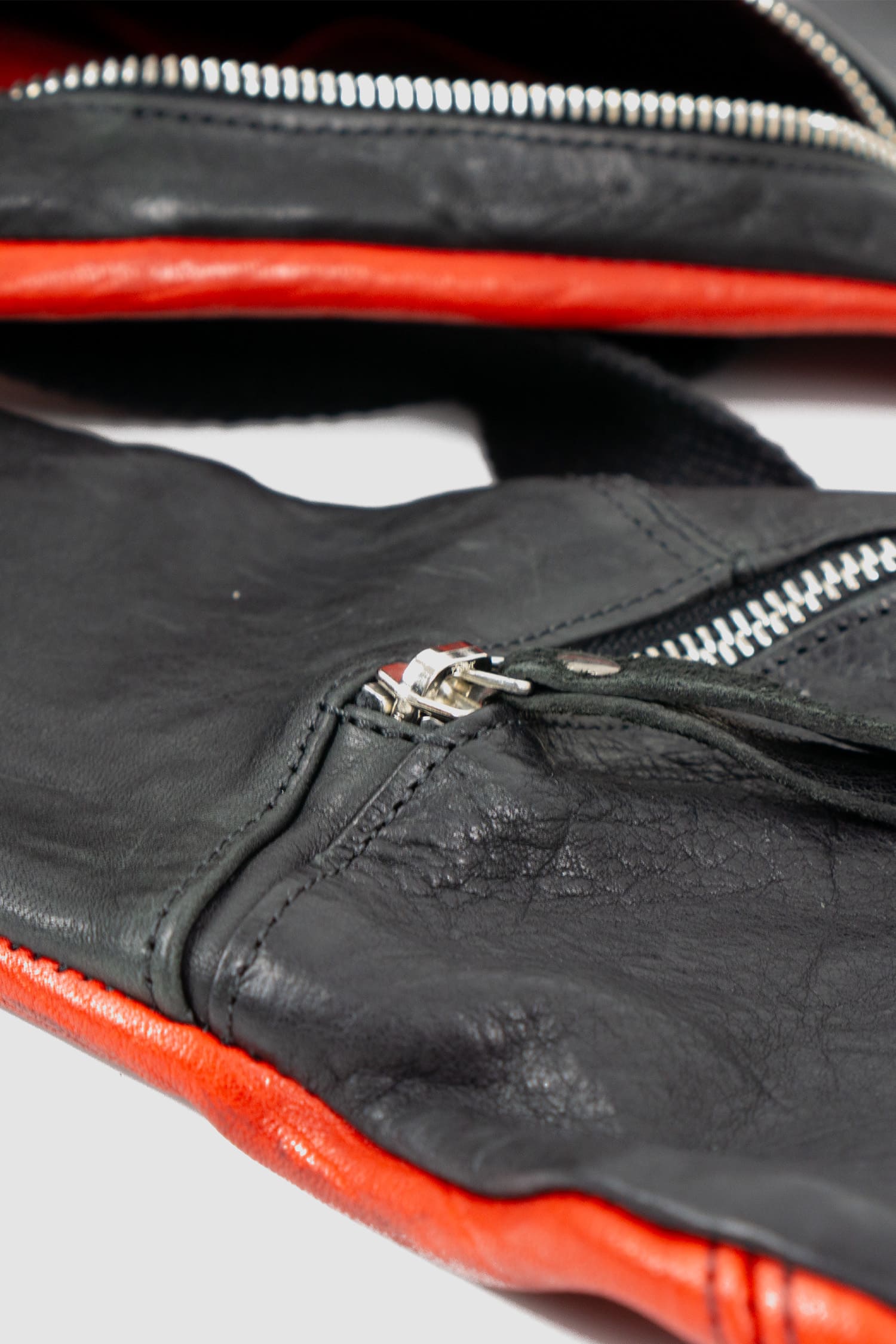0.Hide - zipper detail view of vegetable tanned black and red horsehide leather cargo vest from the permanent collection with two types of horse leather shoulder panels, adjustable cotton straps and zippered pockets.