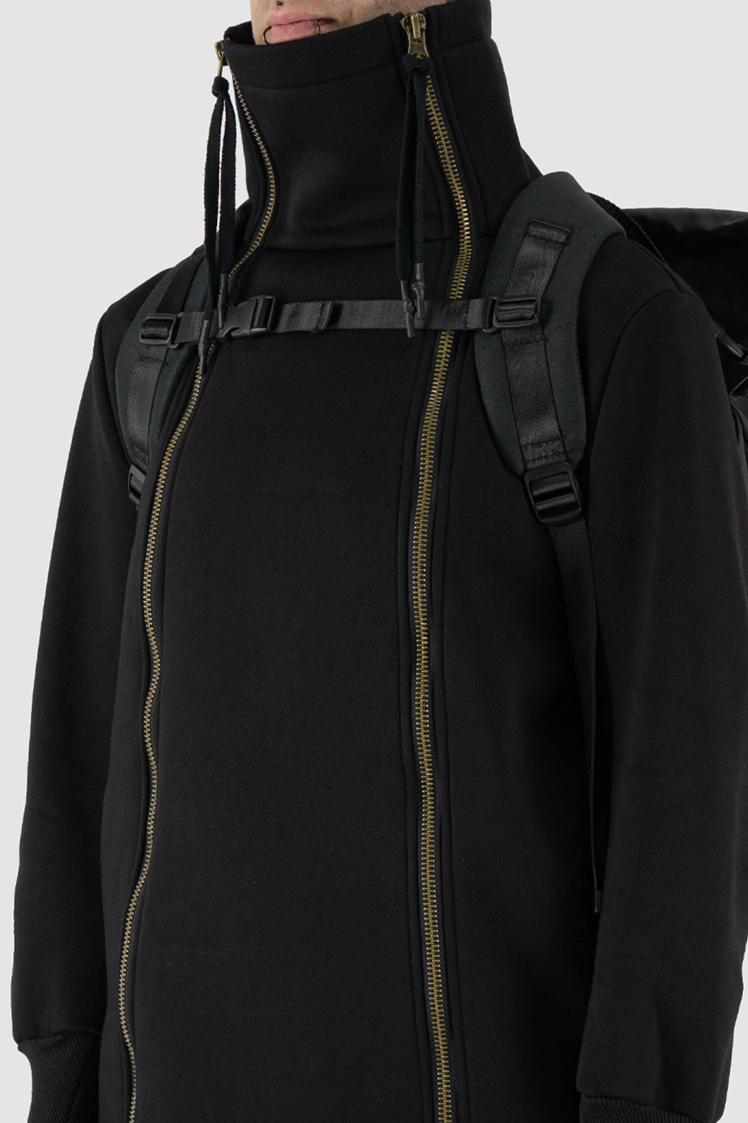 First Aid to the Injured - front detail view of black "Crash against the shore" utility backpack from the permanent collection with hidden cape and roll-top closure and zipper.