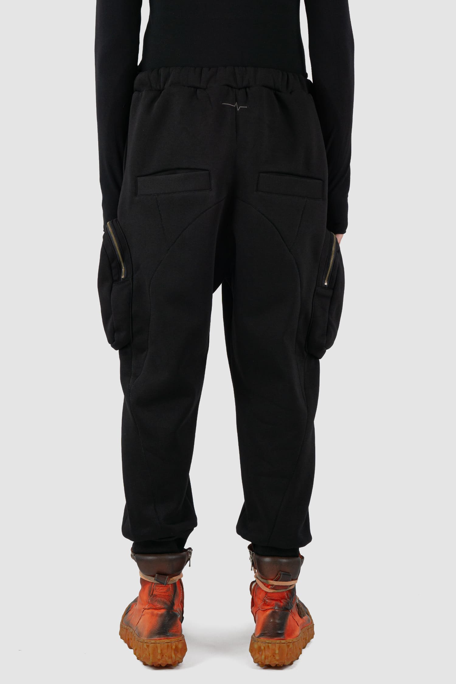 First Aid to the Injured - back view of black tactical cargo joggers with side zip pockets for men from the FW24 collection with semi low crotch design, American fleece and spacious zipper pockets.