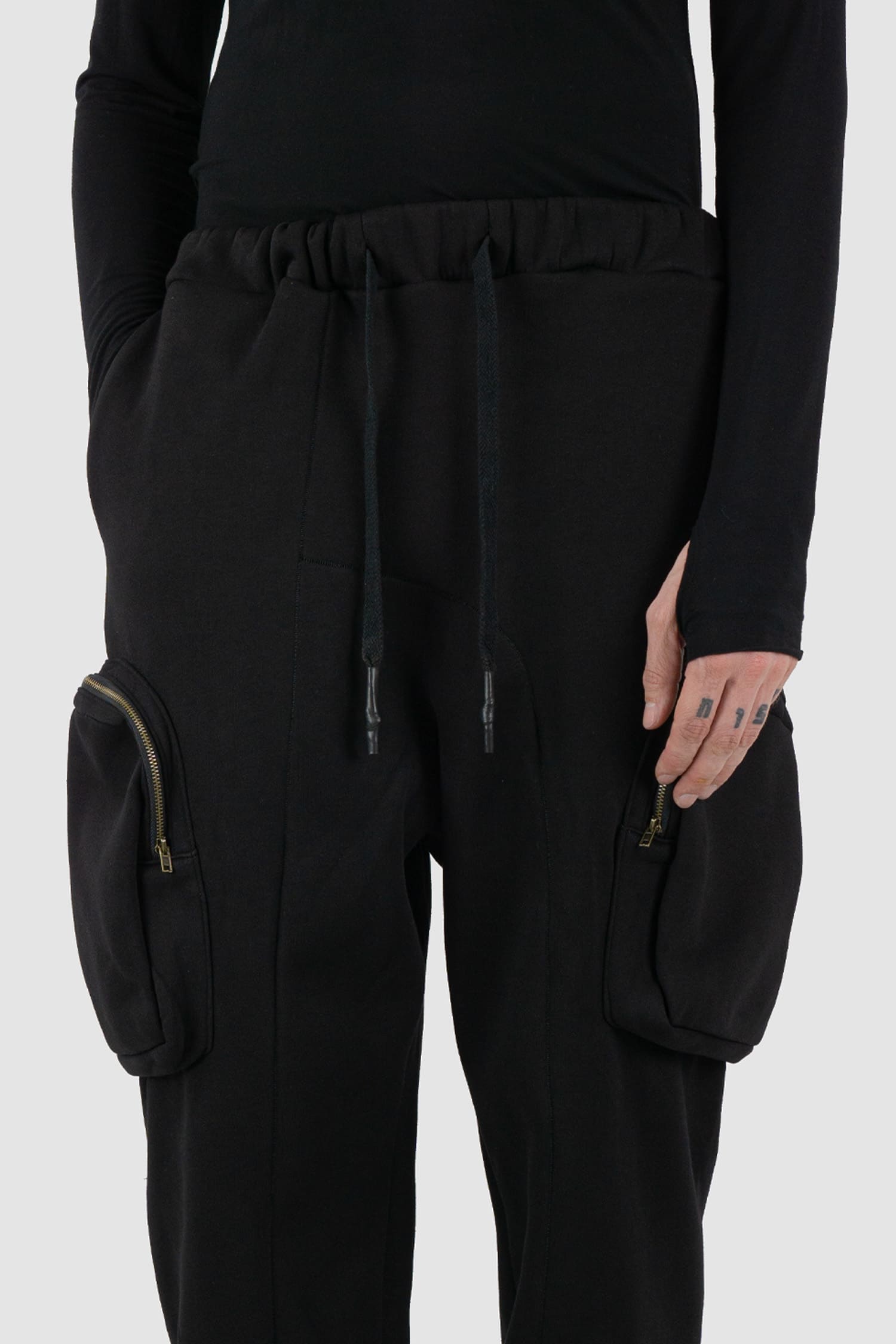 First Aid to the Injured - waist detail view of black tactical cargo joggers with side zip pockets for men from the FW24 collection with semi low crotch design, American fleece and spacious zipper pockets.