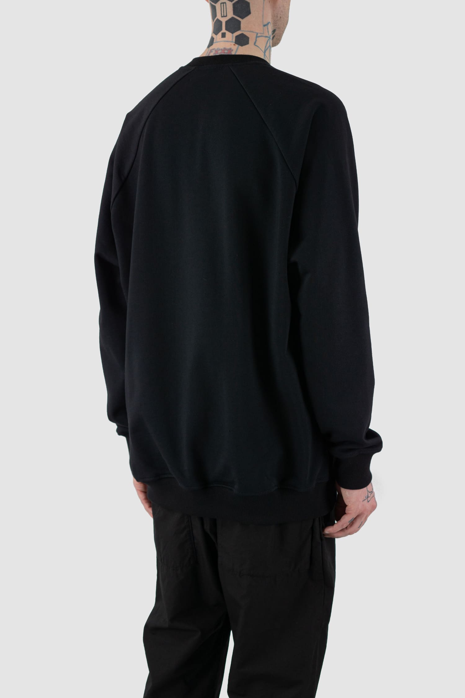 Nomen Nescio - back side view of black cotton raglan sweater with wool rib detail, spacious relaxed fit.