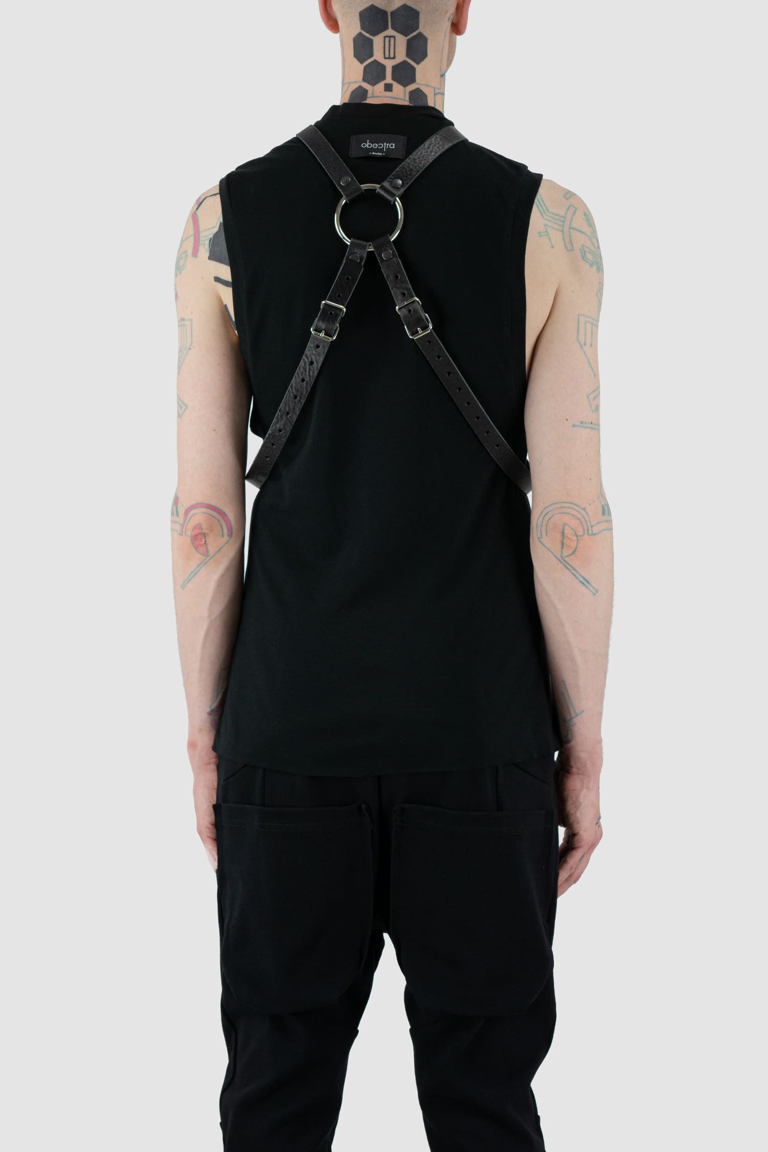 Obectra Studio - Model back view of black double strap leather harness with adjustable buckles, large metal ring, Permanent Collection.