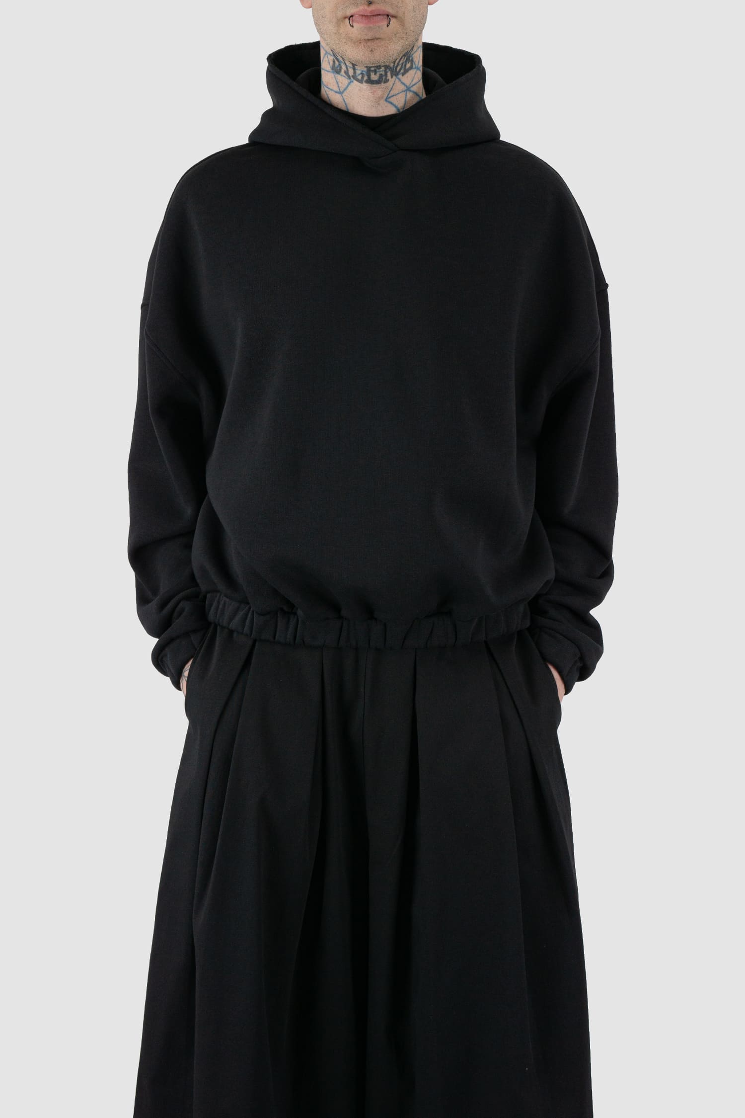 UY Studio - front relax view of black convertible oversized hooded sweater for men from the FW24 collection with semi-raglan shoulders, a large hood and a tight-fitting, flexible belly section.