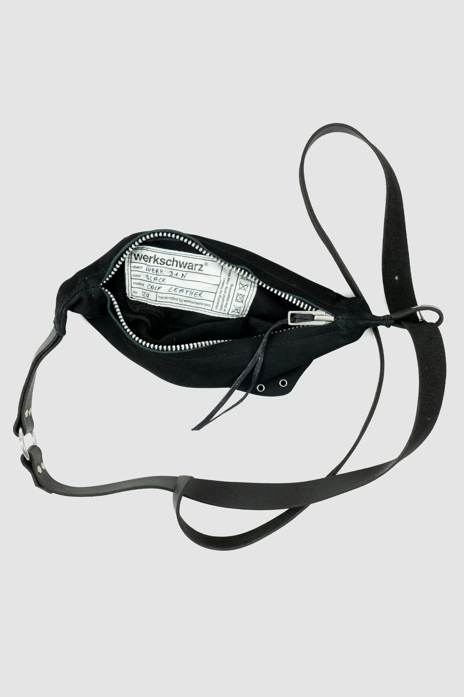 Werkschwarz - Detail view of black silky sanded nubuck leather fanny pack is a versatile accessory that can also be worn as a waist bag or crossbody bag. Part of the Permanent collection, it features a waxed finish, ventilation openings, and a metal ring for added functionality and style.
