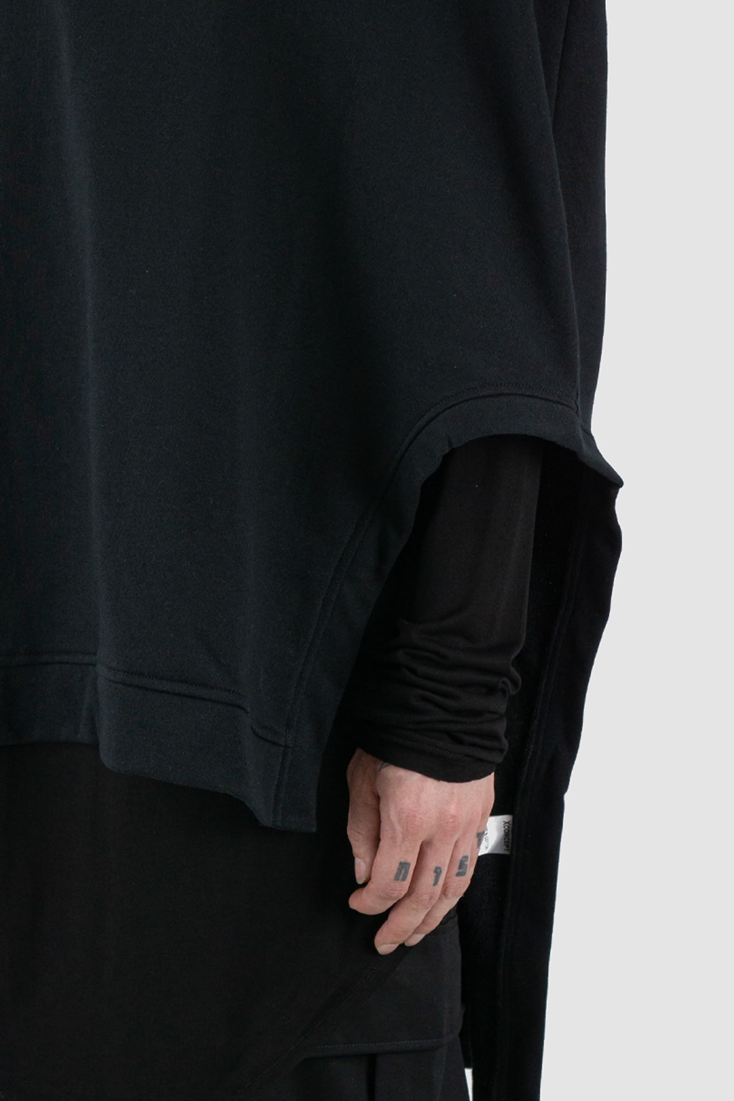 XConcept - arm detail view of black overlapping shoulder high neck top for men with asymmetrical cut, stand-up collar, thick cotton, FW24 Collection.
