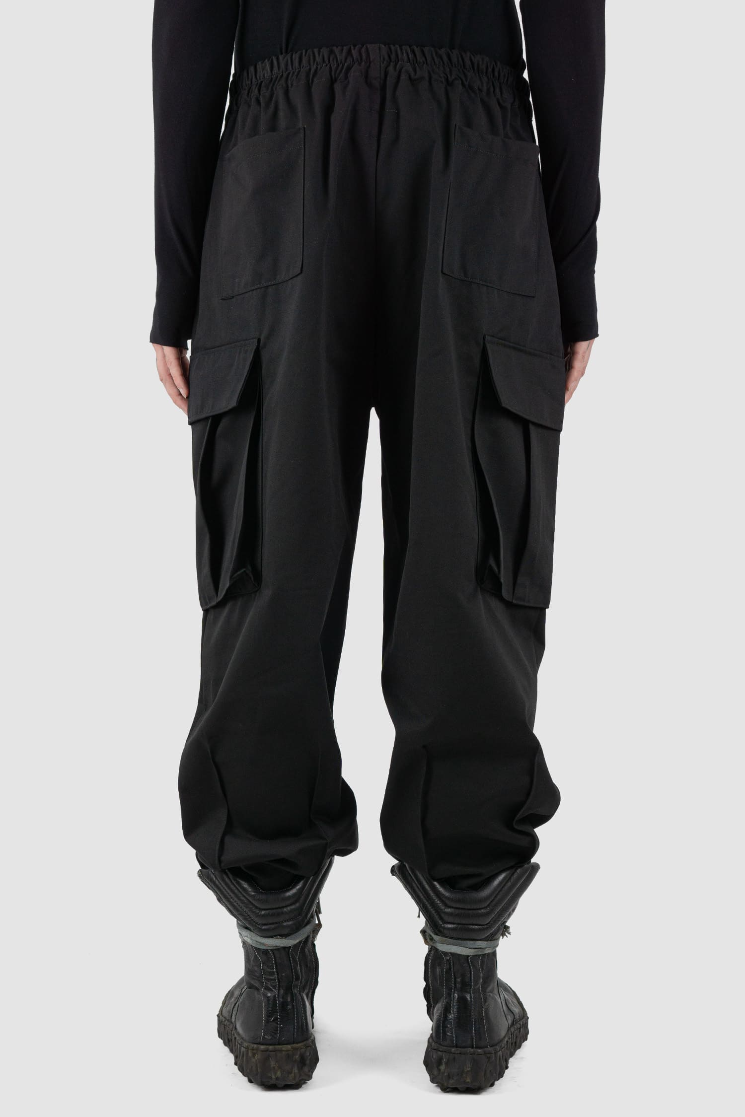 XConcept - back view of black shortened military cargo pants for men with cropped carrot cut, two huge cargo pockets on the sides, FW24 Collection.