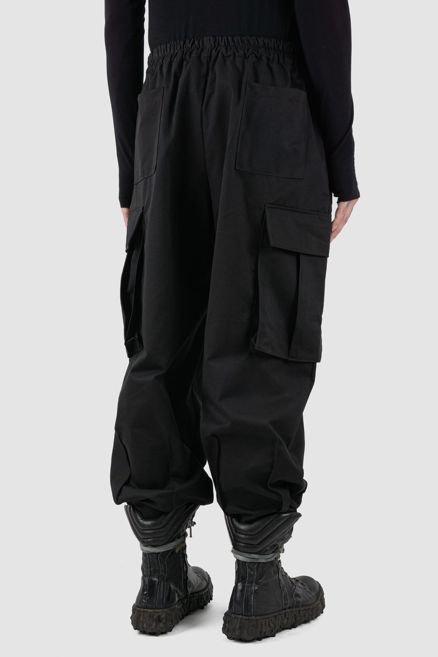 XConcept - back side view of black shortened military cargo pants for men with cropped carrot cut, two huge cargo pockets on the sides, FW24 Collection.