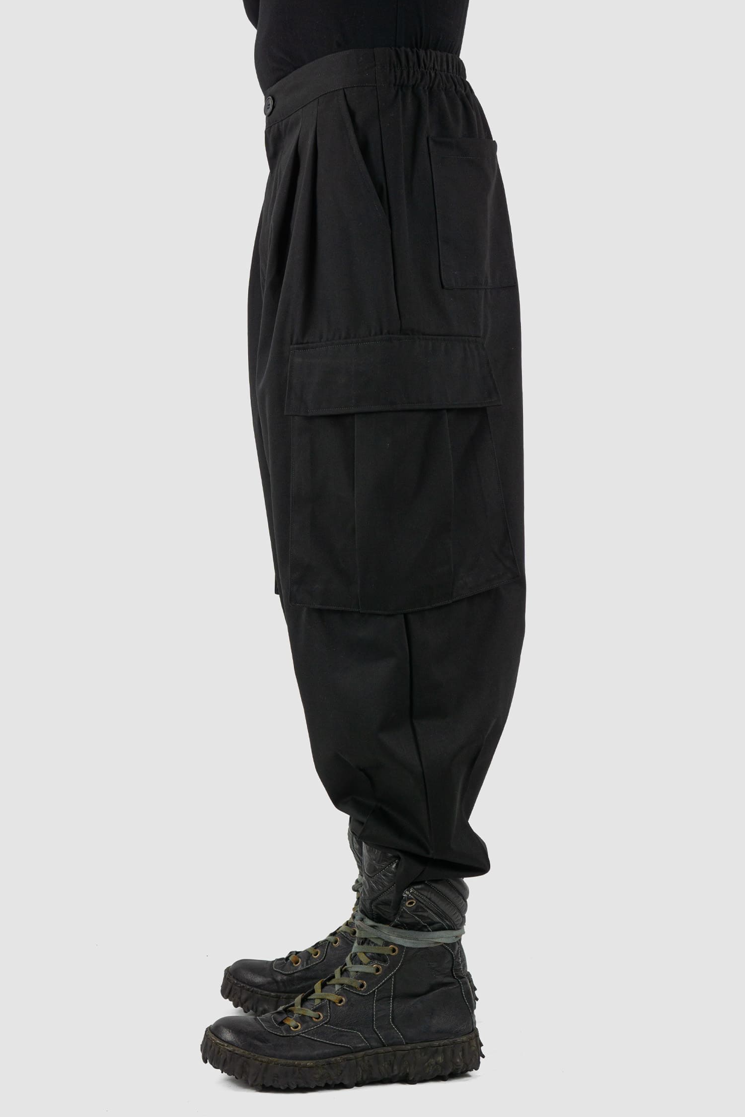 XConcept - side view of black shortened military cargo pants for men with cropped carrot cut, two huge cargo pockets on the sides, FW24 Collection.