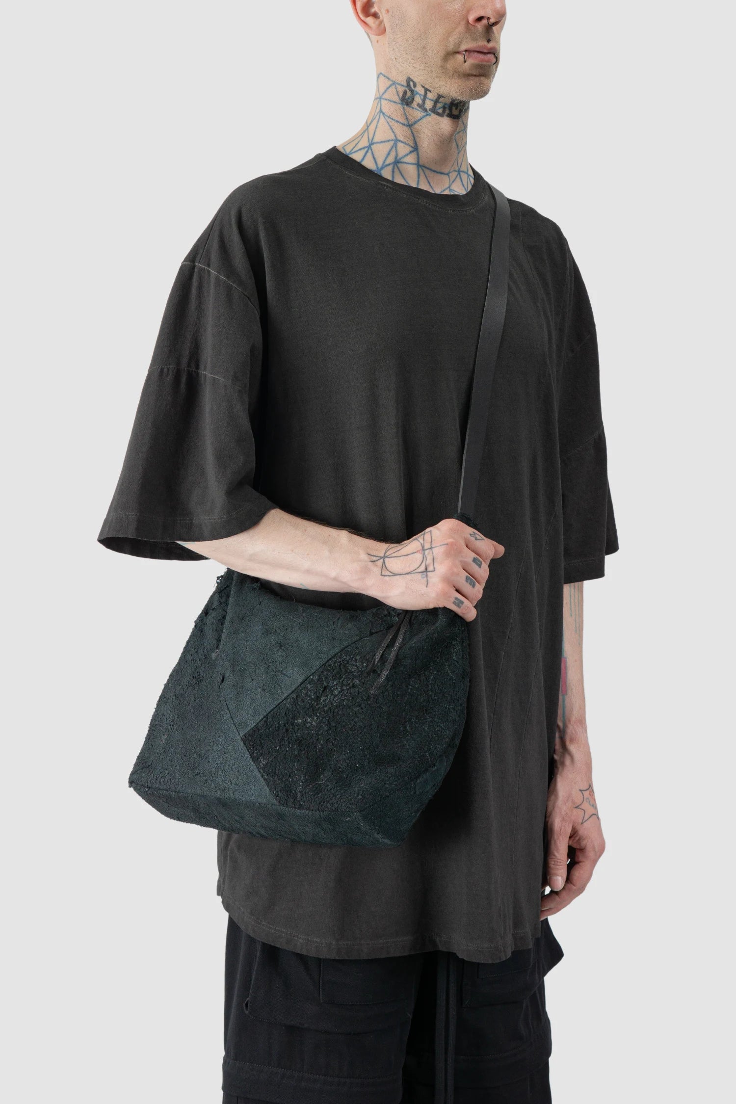 Werkschwarz - model cross over strap view of men’s FW25 Black Raw Leather Shoulder Bag Textured Werk 42G