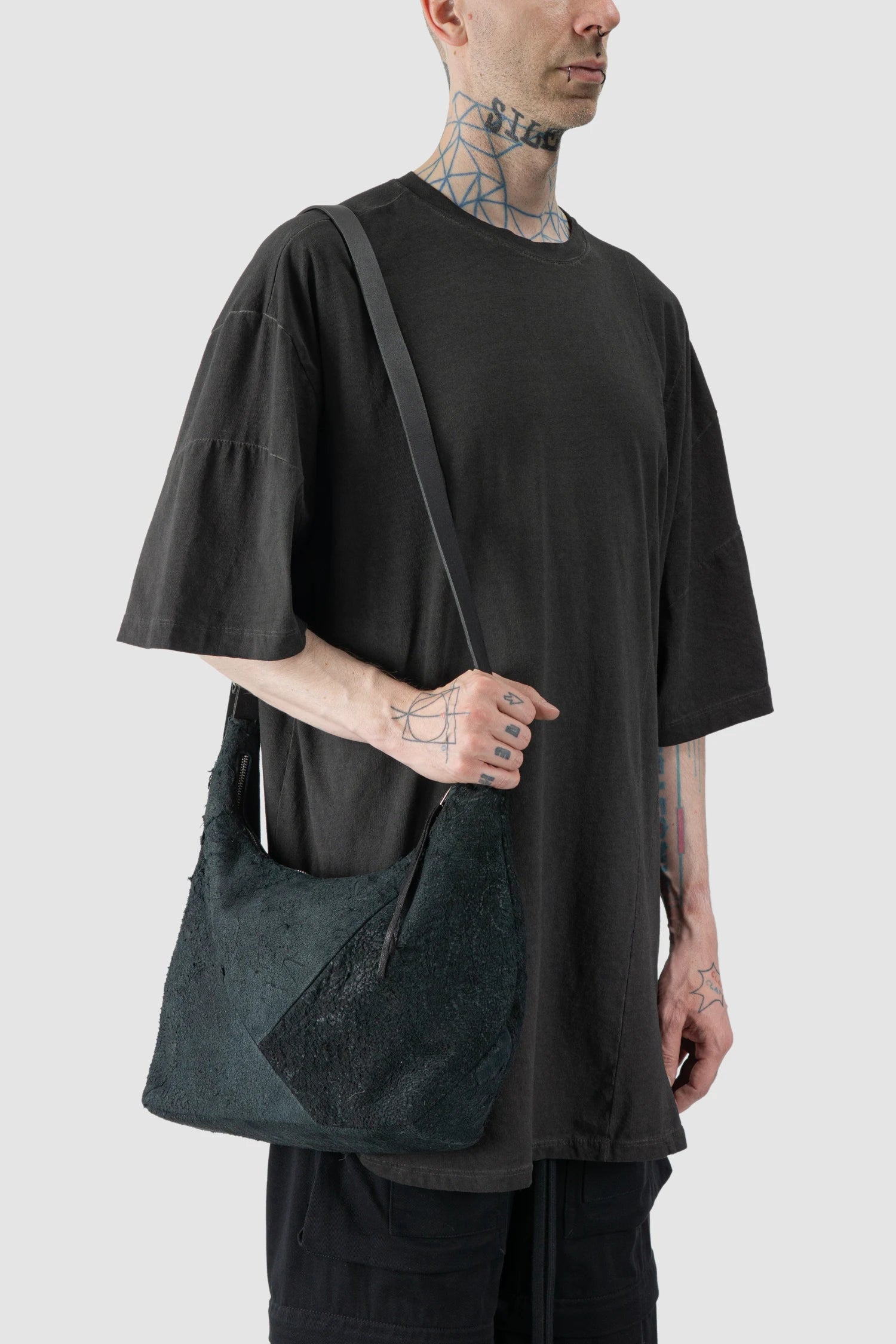 Werkschwarz - model one shoulder view of men’s FW25 Black Raw Leather Shoulder Bag Textured Werk 42G