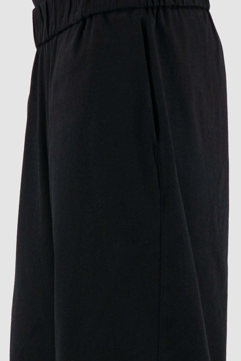 UY STUDIO Black Cotton Zipped Transform Pants: SS24 Collection, wide-legged, loose fit, black. Composition: 97% Cotton, 3% Elastane. Features hidden side seam pockets. Medium-weight fabric with a smooth touch. Detachable lower leg section for over knee shorts. Visible vegan leather UY label on the back.