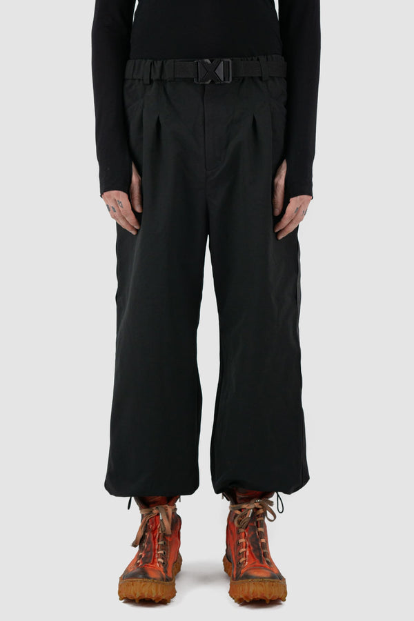 First Aid to the Injured - front view of black belted utility pants with side straps for men from the FW24 collection feature an integrated snap belt and an elasticated parachute hem fastening.