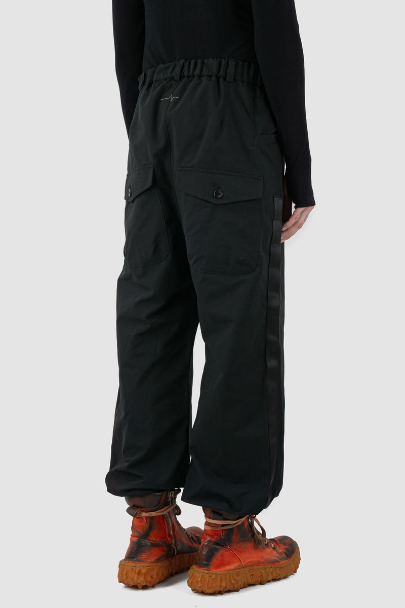 First Aid to the Injured - back side view of black belted utility pants with side straps for men from the FW24 collection feature an integrated snap belt and an elasticated parachute hem fastening.