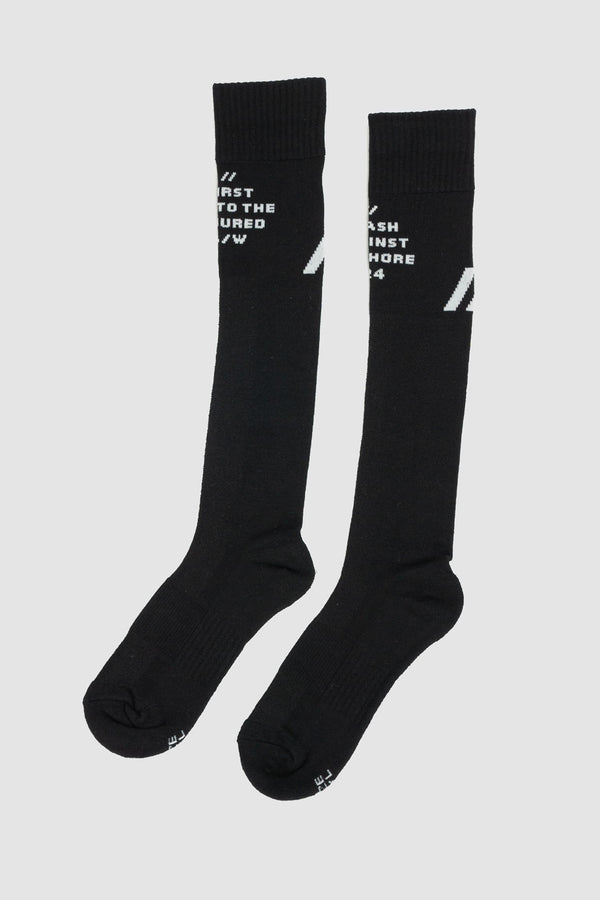 First Aid to the Injured - left view of black "Crash against the shore" logo socks from the FW24 collection with contrasted branding and knee-high design.