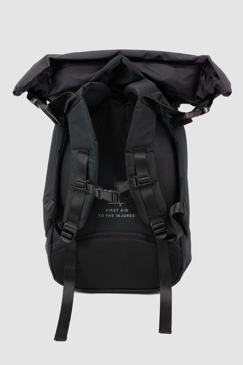 First Aid to the Injured - back solo view of black "Crash against the shore" utility backpack from the permanent collection with hidden cape and roll-top closure and zipper.