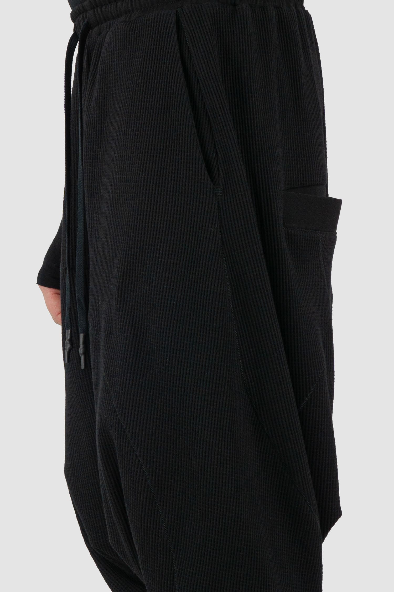 First Aid to the Injured - side view of black drop crotch waffle cotton joggers for men from the FW24 collection with elastic waistband and drawstring as well as 2 back and 2 side pockets.