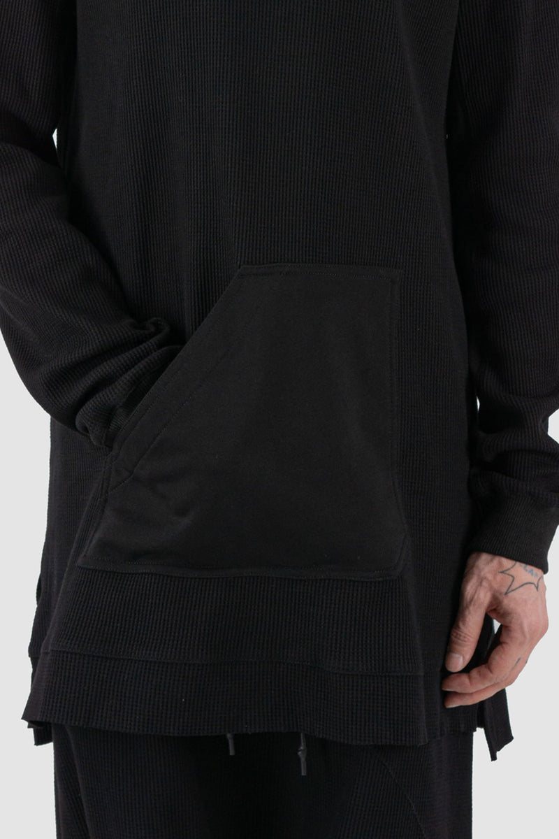 First Aid to the Injured - front detail view of black long waffle textured cotton jersey sweater for men from the FW24 collection. Featured a kangaroo pocket, contrasting arm panels and side slits.