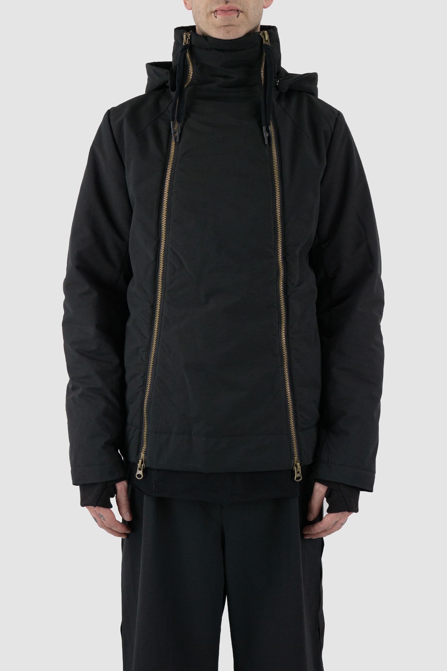 First Aid to the Injured - front view of black padded jacket with double zipper closure for men from the FW24 collection with detachable hood, 2 long zippers to close the jacket and knitted-in cuffs with thumb holes.
