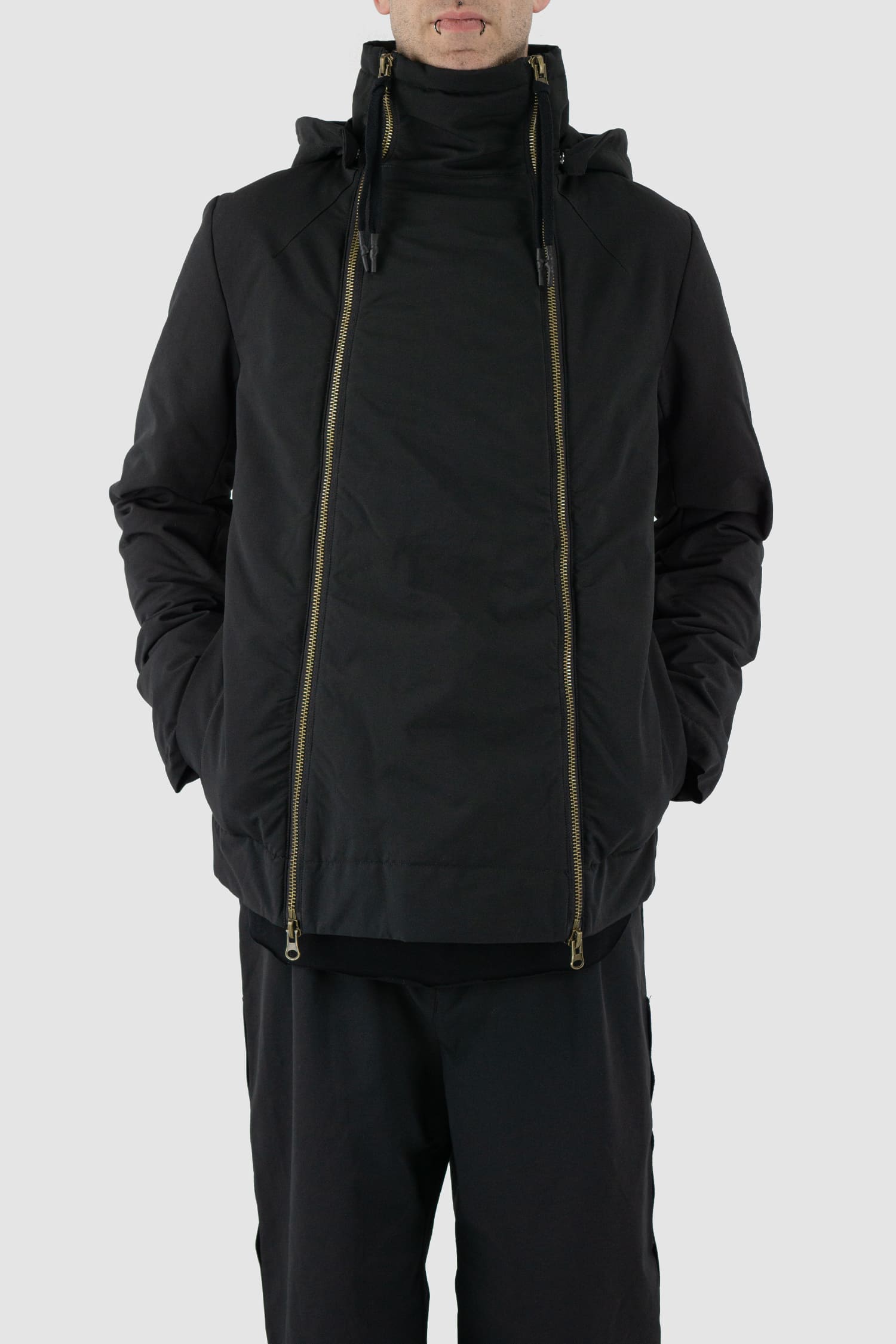 First Aid to the Injured - front relax view of black padded jacket with double zipper closure for men from the FW24 collection with detachable hood, 2 long zippers to close the jacket and knitted-in cuffs with thumb holes.