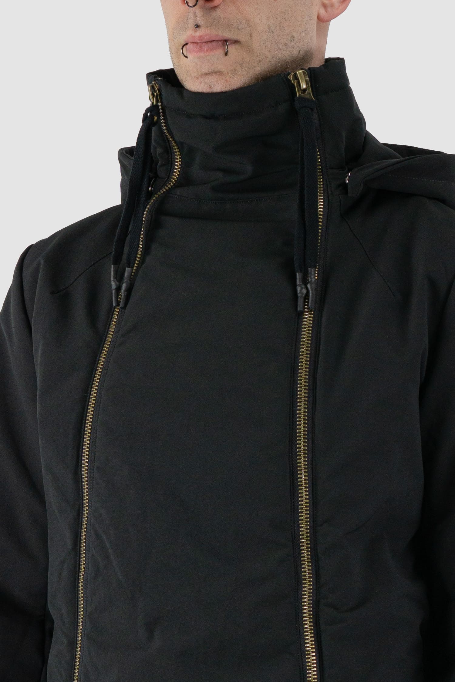 First Aid to the Injured - front detail view of black padded jacket with double zipper closure for men from the FW24 collection with detachable hood, 2 long zippers to close the jacket and knitted-in cuffs with thumb holes.