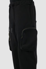 First Aid to the Injured - pocket view of black tactical cargo joggers with side zip pockets for men from the FW24 collection with semi low crotch design, American fleece and spacious zipper pockets.