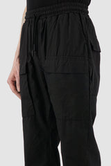 Nomen Nescio - detail view of black light pocket pants with elastic waistband, patched front pockets.