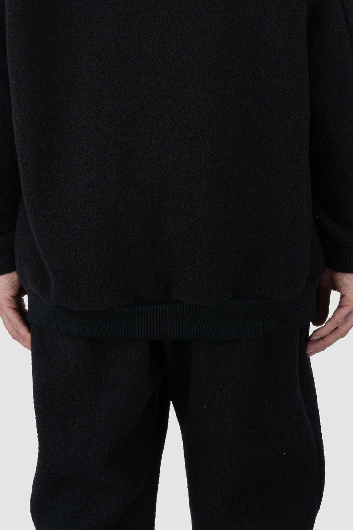 Nomen Nescio - back hem view of black recycled wool hoodie 518 for men from the FW24 collection offers a roomy fit with a large hood and wool rib details on the hem and cuffs.