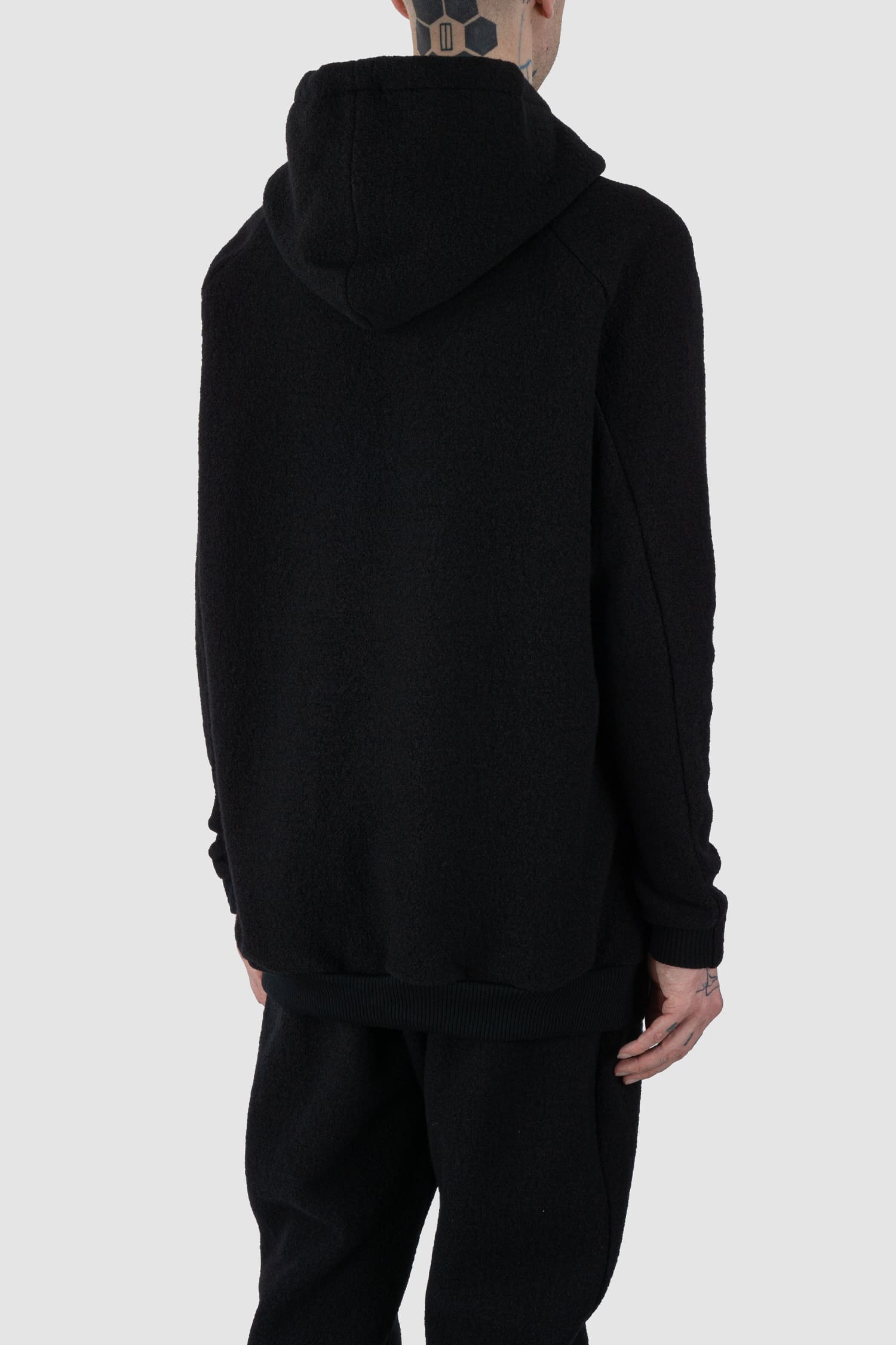 Nomen Nescio - back side view of black recycled wool hoodie 518 for men from the FW24 collection offers a roomy fit with a large hood and wool rib details on the hem and cuffs.