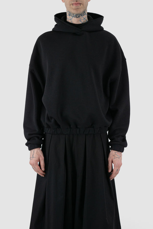 UY Studio - front view of black convertible oversized hooded sweater for men from the FW24 collection with semi-raglan shoulders, a large hood and a tight-fitting, flexible belly section.