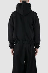 UY Studio - back view of black convertible oversized hooded sweater for men from the FW24 collection with semi-raglan shoulders, a large hood and a tight-fitting, flexible belly section.