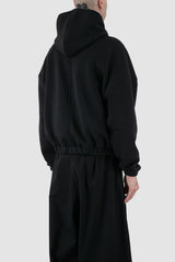 UY Studio - back side view of black convertible oversized hooded sweater for men from the FW24 collection with semi-raglan shoulders, a large hood and a tight-fitting, flexible belly section.