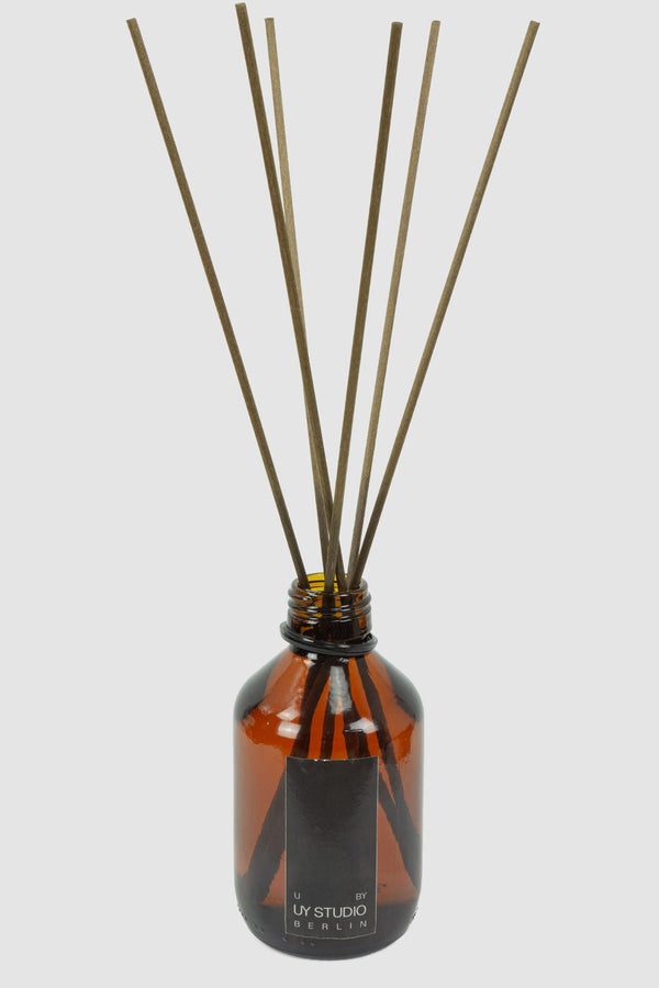 UY Studio - Front view of Signature Room Diffuser U in 200ml amber glass flacon with 8 rattan earth-toned sticks, Permanent Collection.