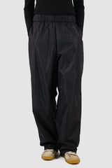 UY Studio - Front legere view of black nylon wide fisher pants with elastic waistband, loose fit.