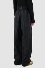 UY Studio - back side view of black nylon wide fisher pants with elastic waistband, loose fit.