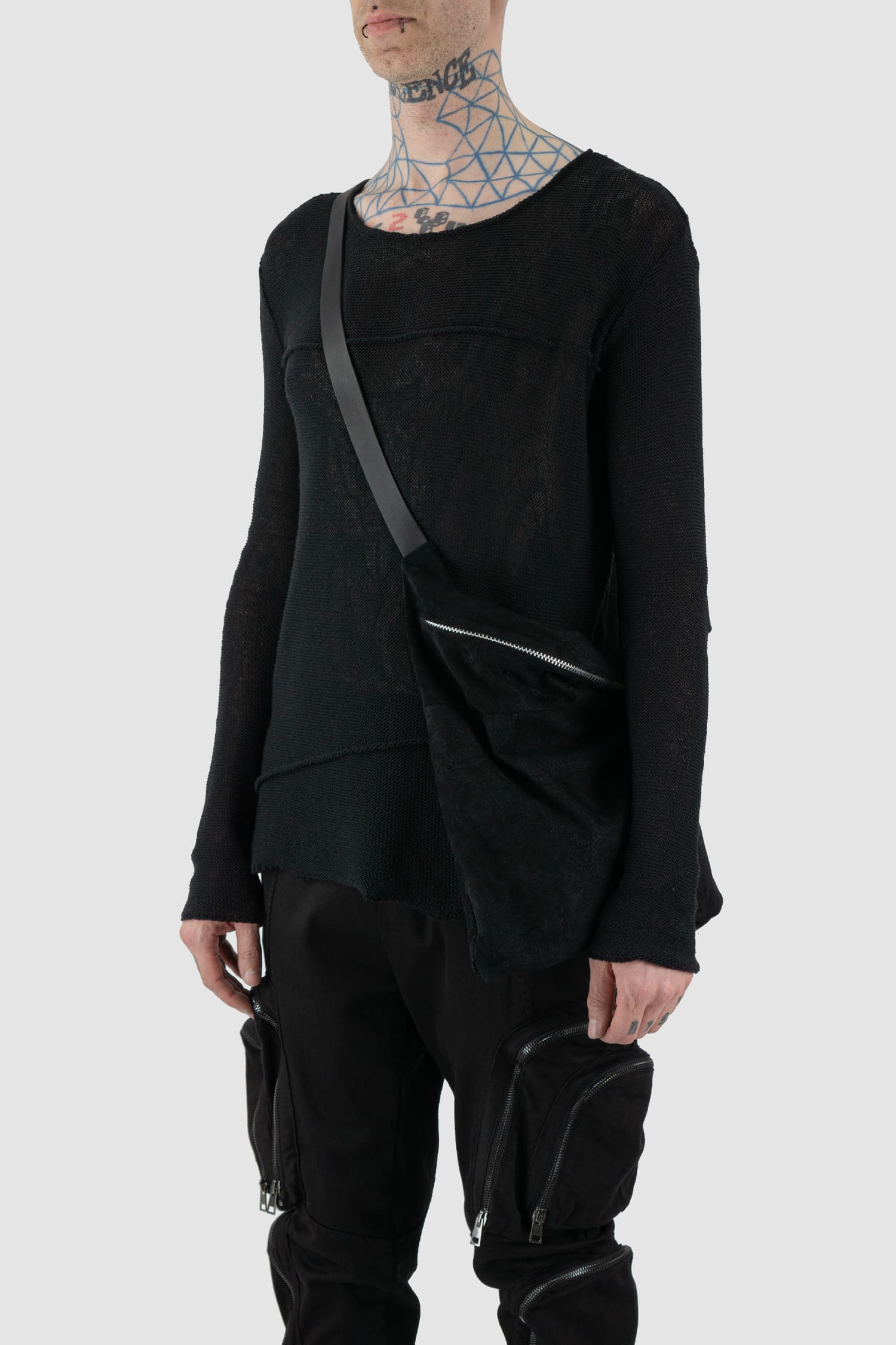 Werkschwarz - Model side view of black waxed reversed leather one-shoulder pack bag is the ideal piece to wear crossbody from the Permanent collection. It features a waxed finish, an origami shape, and a heavy-duty YKK zipper, combining functionality with contemporary design.