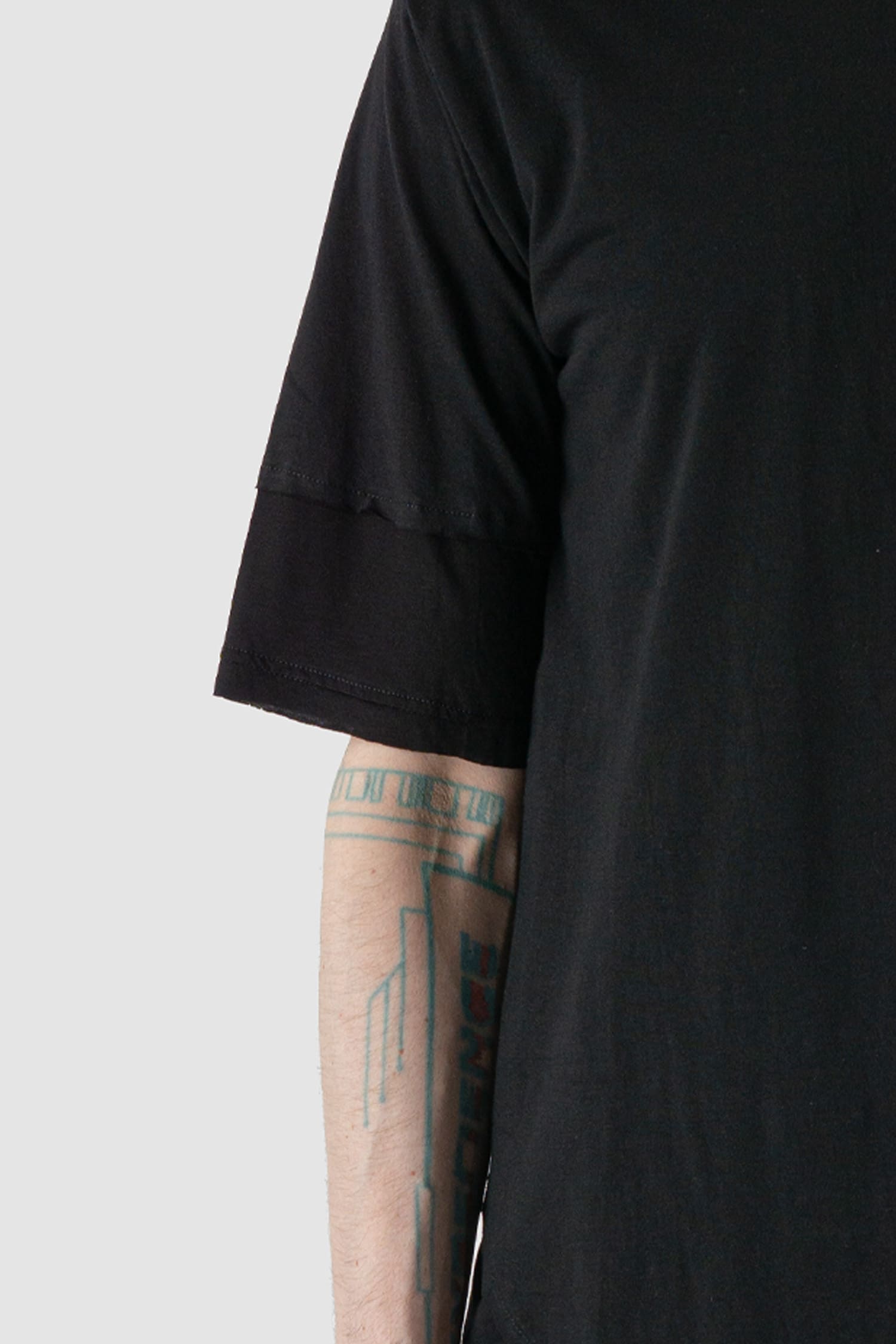 XConcept - arm detail view of black asymmetric pointed Tack T-shirt for men with double-layer sleeves, pointed tapered front, FW24 Collection.