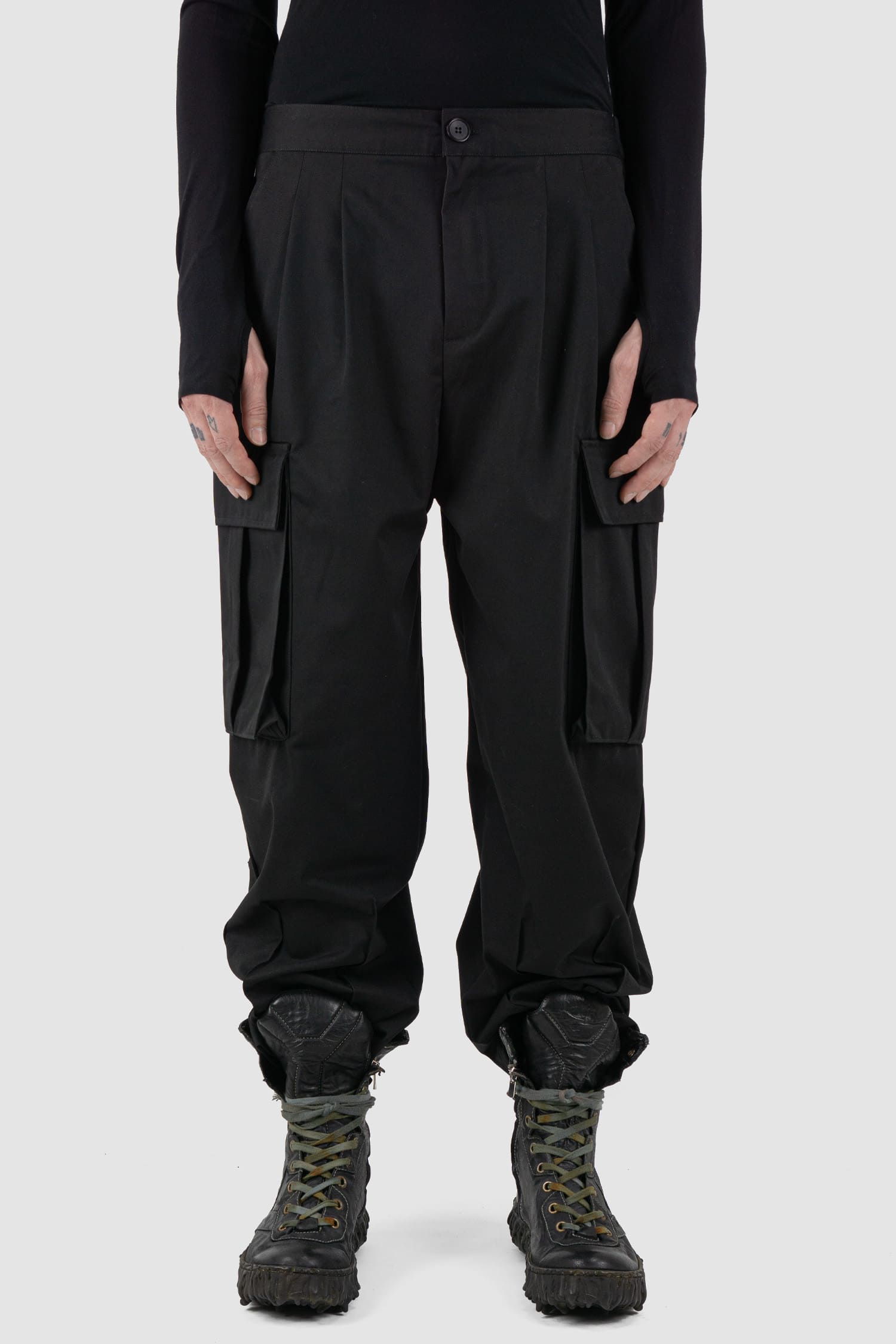 XConcept - Front view of black shortened military cargo pants for men with cropped carrot cut, two huge cargo pockets on the sides, FW24 Collection.