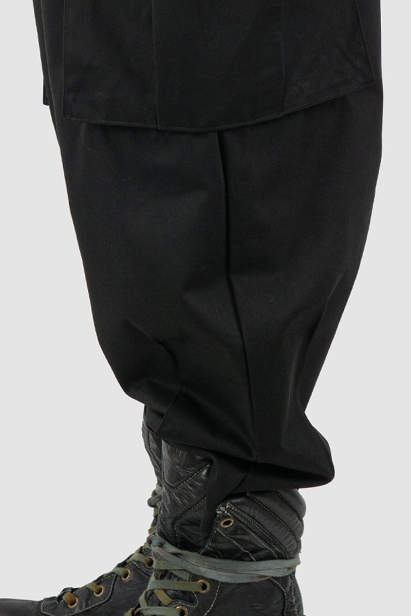 XConcept - hem view of black shortened military cargo pants for men with cropped carrot cut, two huge cargo pockets on the sides, FW24 Collection.