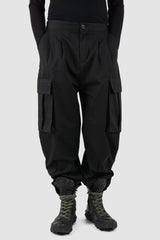 XConcept - Front legere view of black shortened military cargo pants for men with cropped carrot cut, two huge cargo pockets on the sides, FW24 Collection.